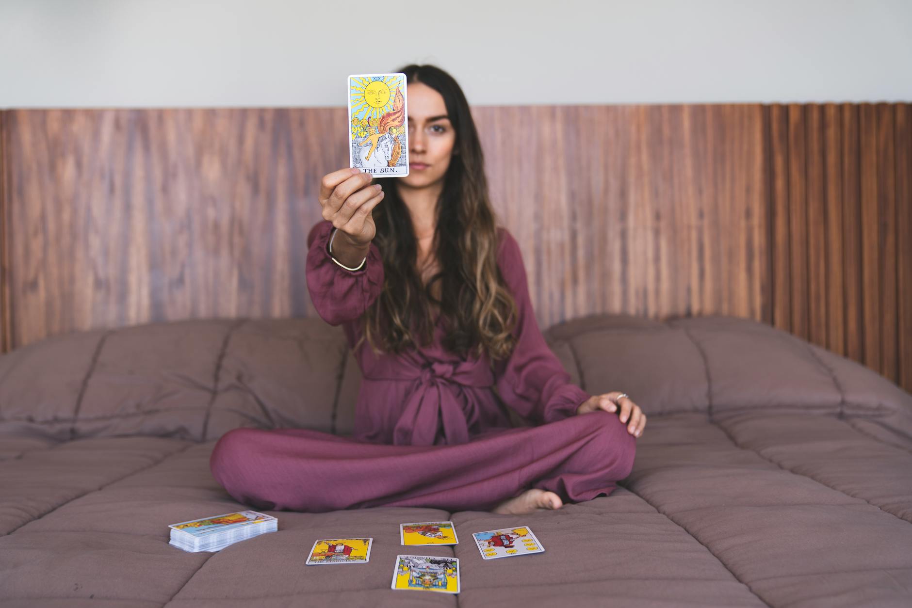 curly haired female holding a tarot card